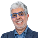 Smiling older man with gray hair, glasses, and a beard wearing a blue blazer and light blue shirt, posed against a plain white background—perfect for professional profiles or Cybericon2024 event materials.